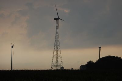 Low angle view of silhouette windmill on field against sky