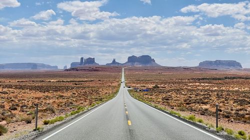 Empty road along landscape against sky