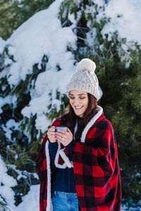 Smiling woman standing with coffee cup in snow