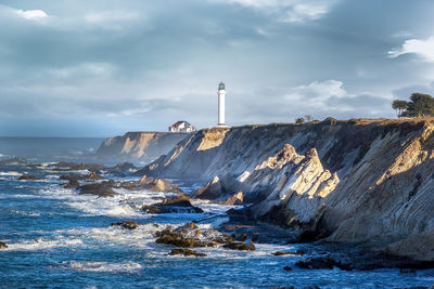 Lighthouse by sea against sky