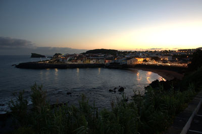 View of town at sea during sunset