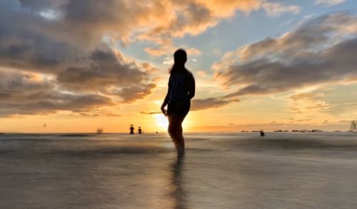 Silhouette man standing on beach against sky during sunset