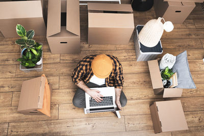 Happy mature man sitting on the floor of a newly rented ore purchased apartment using a laptop.