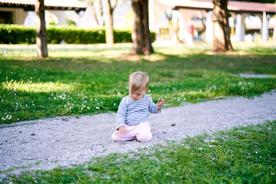 Full length of boy sitting on field