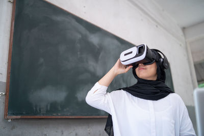 Smiling young woman using virtual reality in classroom