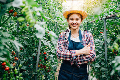 Portrait of young woman standing amidst flowering plants