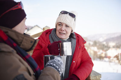 Mature couple with hot drinks talking outdoors in winter