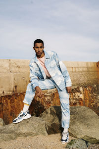 Man wearing clouds denim suit staring while standing on stone