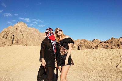 Portrait of young couple standing on desert against clear sky