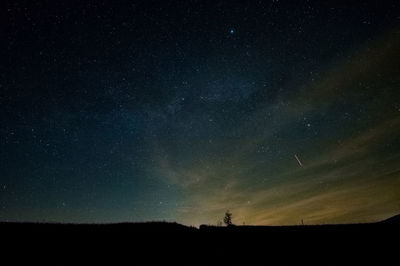 Silhouette landscape against star field at night