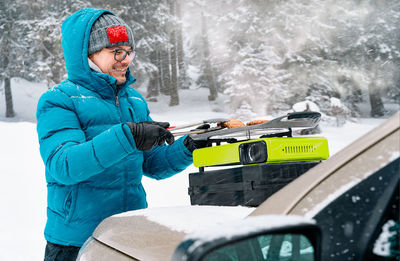 Smiling man cooking food on camping stove in winter forest