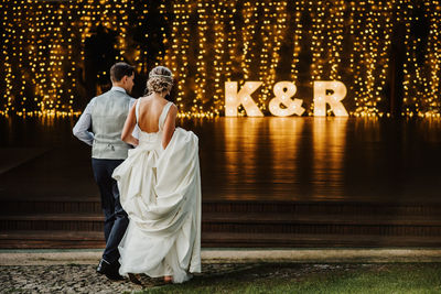 Rear view of friends standing on illuminated street at night