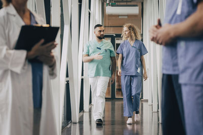 Male medical professional explaining colleague while walking in corridor of hospital