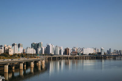 River by buildings against clear sky