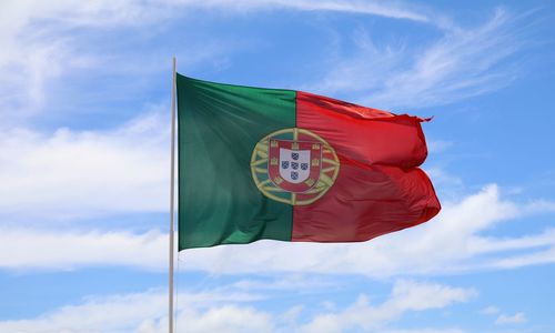 Low angle view of portuguese flag against cloudy blue sky