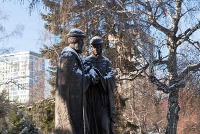 Monument to saints peter and fevronia the symbols of love and fidelity against the trees and houses.