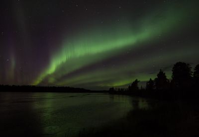 Scenic view of lake with aurora borealis against sky at night