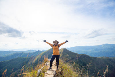 Rear view of man standing on mountain against sky