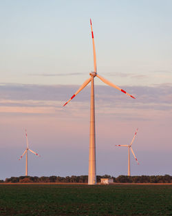 Windmills on field against sky