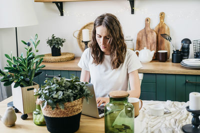 Beautiful woman in the kitchen working on a laptop.