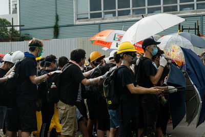 Rear view of people on street in rain