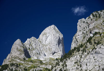 Low angle view of rocky mountain against blue sky