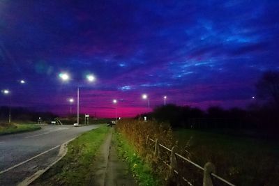 Illuminated road against sky at night