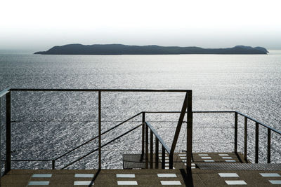 High angle view of steps by sea against clear sky