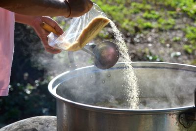 Close-up of hand pouring water in container