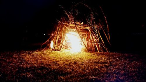 Close-up of illuminated bonfire on field against sky at night