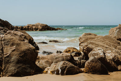 Rocks on beach against clear sky