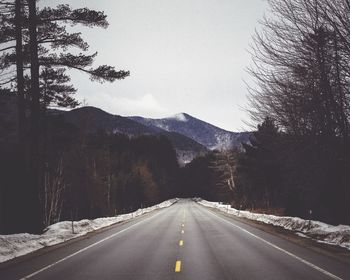 Empty road by mountains against sky