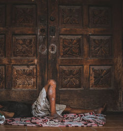 Low section of man sleeping on floor by closed door
