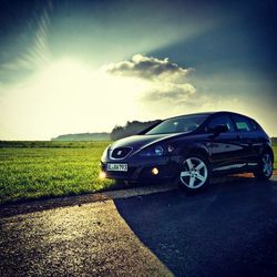 Sun shining through clouds over field