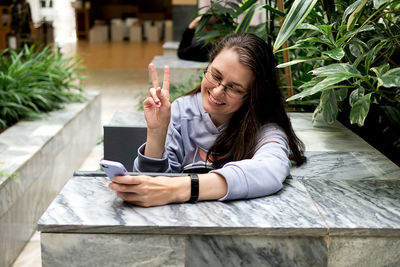 Young brunette girl uses mobile phone texting smartphones messages in botanical garden