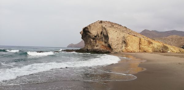 Rock formation on beach against sky