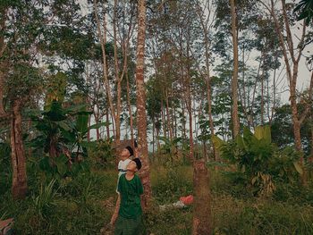 Woman standing by trees in forest