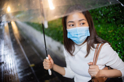 Portrait of woman holding umbrella in rain