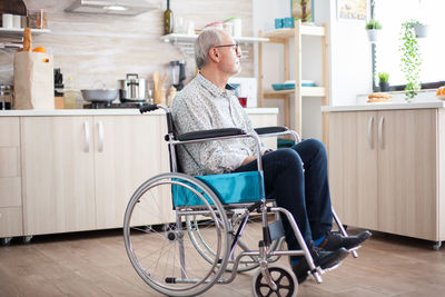 Senior man sitting on wheelchair at home
