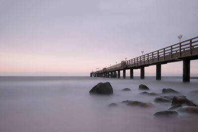 Bridge over sea against sky during sunset