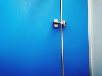 Low angle view of electric lamp against blue wall