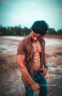 Young man looking away while standing on land