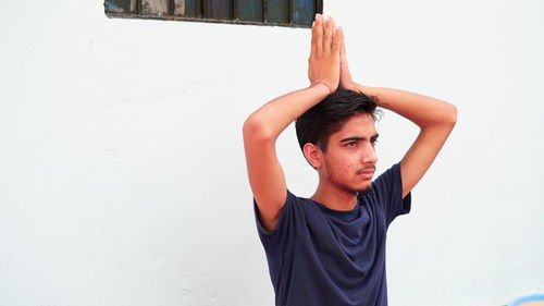 Portrait of young man standing against wall