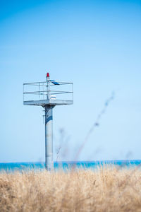 Lifeguard hut on field against clear blue sky