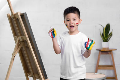 Side view of boy painting on canvas at home