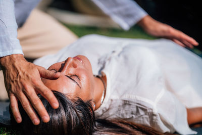 Close-up image of relaxed woman lying with her eyes closed and having reiki healing treatment 