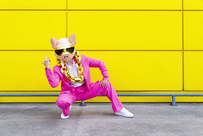 Woman wearing sunglasses against yellow wall