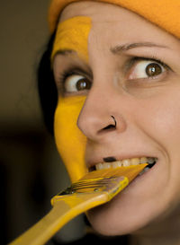 Close-up portrait of young woman eating yellow