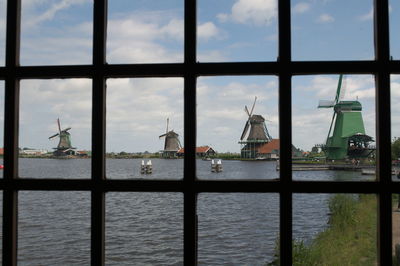 River in front of windmills seen through window