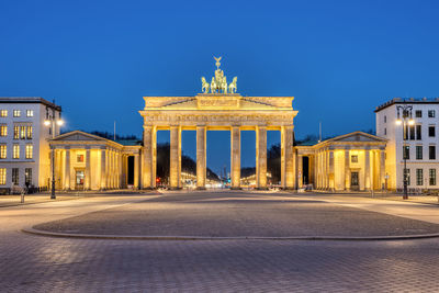 The illuminated brandenburg gate in berlin at dawn